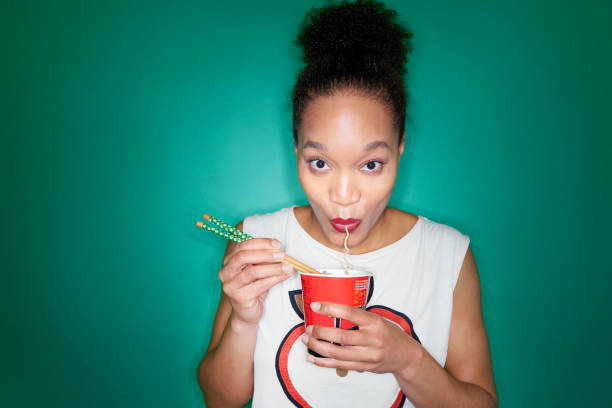 woman eating noodles - junk food stockfoto's en -beelden