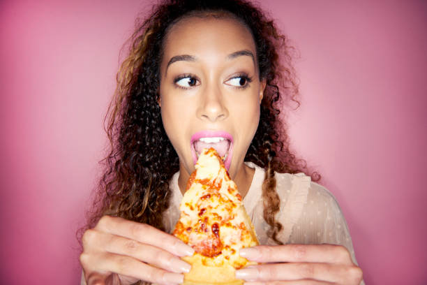 woman eating pizza slice - junk food stock pictures, royalty-free photos & images