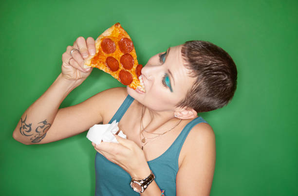 woman eating pizza slice - junk food stockfoto's en -beelden