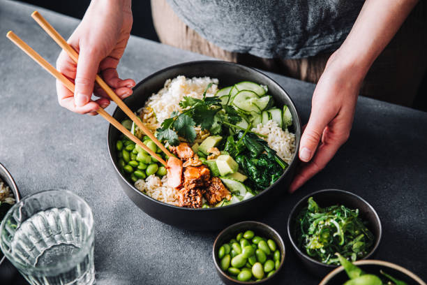 woman eating poke salad with chopsticks - food stockfoto's en -beelden