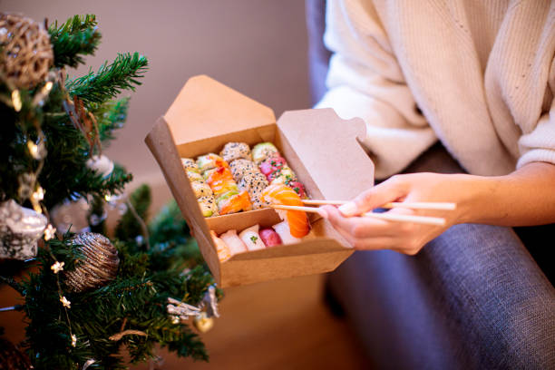 woman eats takeaway sushi at christmas - junk food stock pictures, royalty-free photos & images