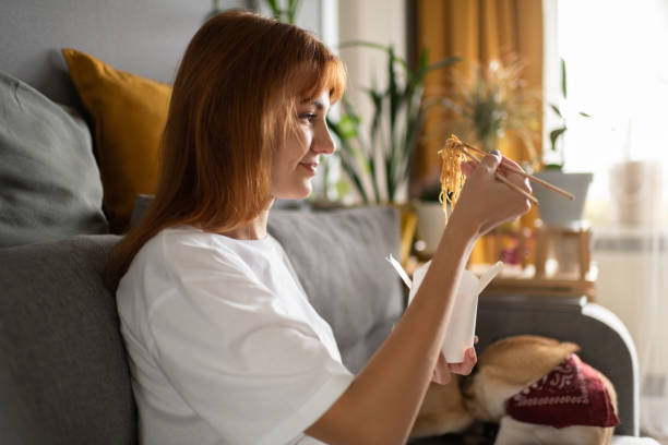 woman enjoying noodles near dog - junk food stock pictures, royalty-free photos & images