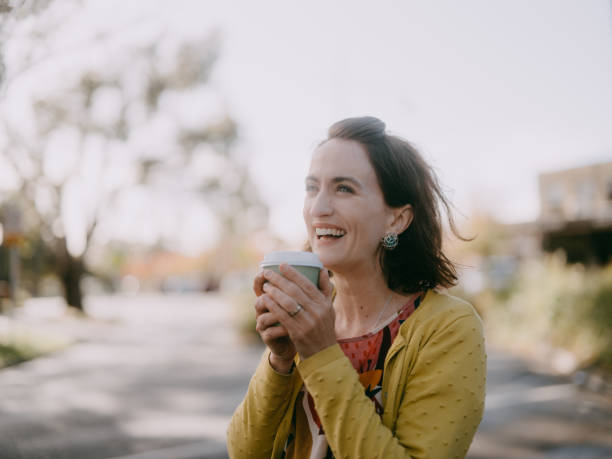 woman enjoying takeaway coffee in suburb - junk food stock pictures, royalty-free photos & images