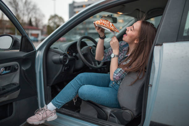 woman enjoys eating pizza on parking lot - junk food stock pictures, royalty-free photos & images