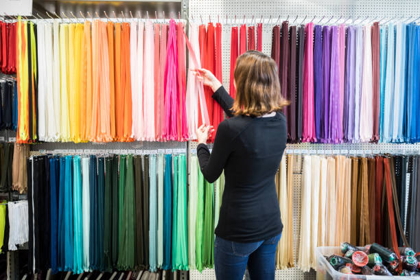 woman examining colorful zippers on rack in store - fashion stock pictures, royalty-free photos & images