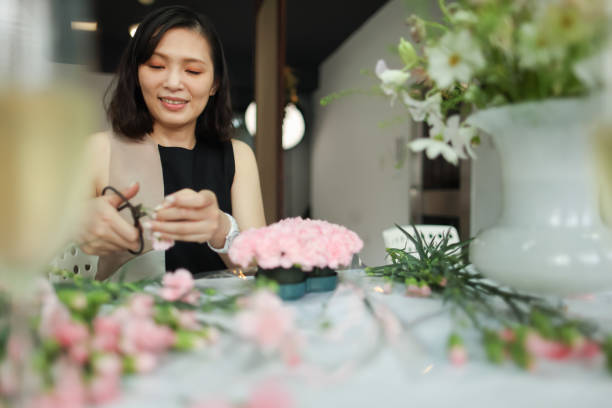 woman focused on flower arrangement creation - garden decoration stock pictures, royalty-free photos & images
