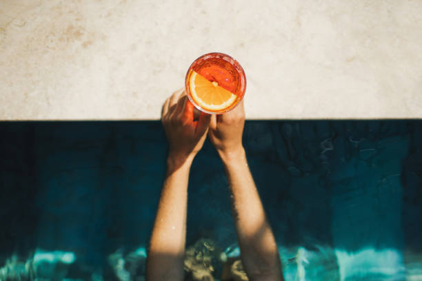 woman hands holding spritz cocktail on poolside close-up. leisure and relaxation concept, cold summer drink - food stock pictures, royalty-free photos & images