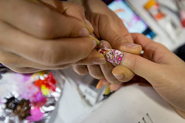 Woman has her choosen anime character painted onto her fingernails at Ita Color's Yellow nail salon on February 27, 2014 in Akihabara district,...