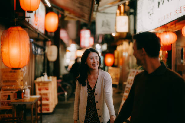 woman having a good time with her boyfriend in tokyo at night - travel stock pictures, royalty-free photos & images