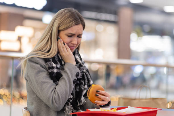 woman having toothache from burger - junk food stock pictures, royalty-free photos & images
