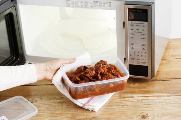 woman heating leftovers in microwave - food stock pictures, royalty-free photos & images