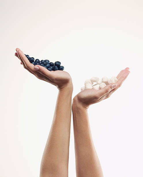 woman holding handful of blueberries over handful of sugar cubes - junk food stock pictures, royalty-free photos & images
