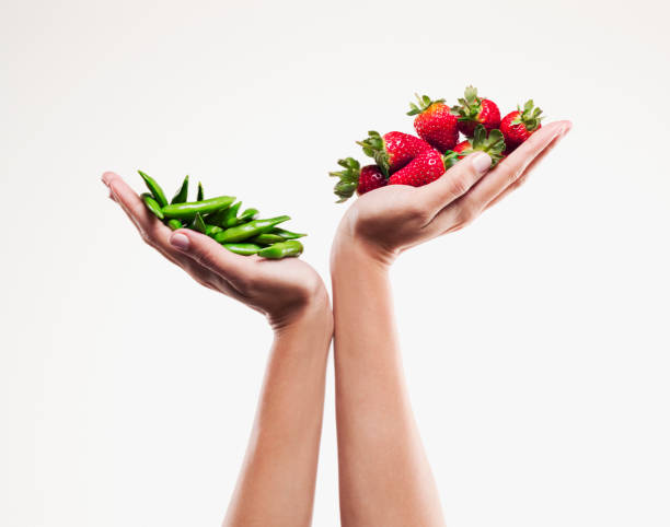 woman holding handful of strawberries over handful of pea pods - food stock pictures, royalty-free photos & images