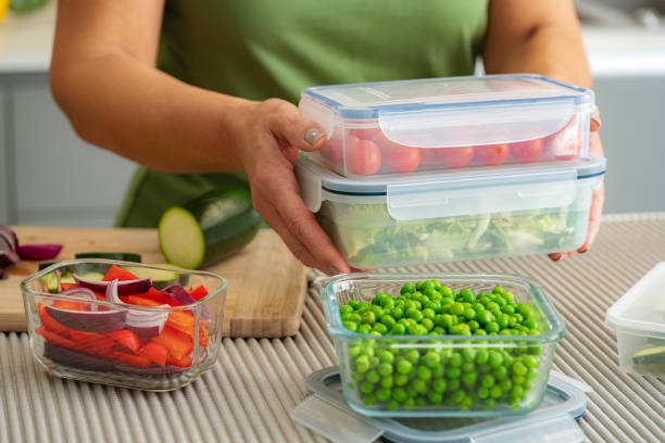 woman holding plastic airtight food containers filled with vegetables ready for be stored in the refrigerator - food stock pictures, royalty-free photos & images