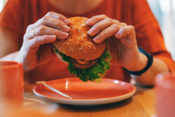 woman holding vegetarian plant based burger - junk food stock pictures, royalty-free photos & images
