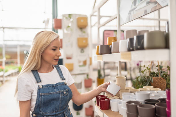 woman in garden store chooses pots and pots for her plants in shopping mall, greenhouse site - garden decoration stockfoto's en -beelden