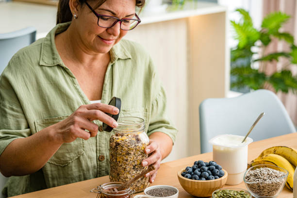 woman is about to prepare healthy nutritious breakfast. oatmeal , honey, berries, seeds, fruits - food stock pictures, royalty-free photos & images