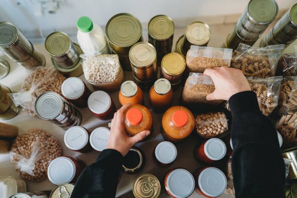 woman is rearranging the nonperishable food at the food bank - food stock pictures, royalty-free photos & images
