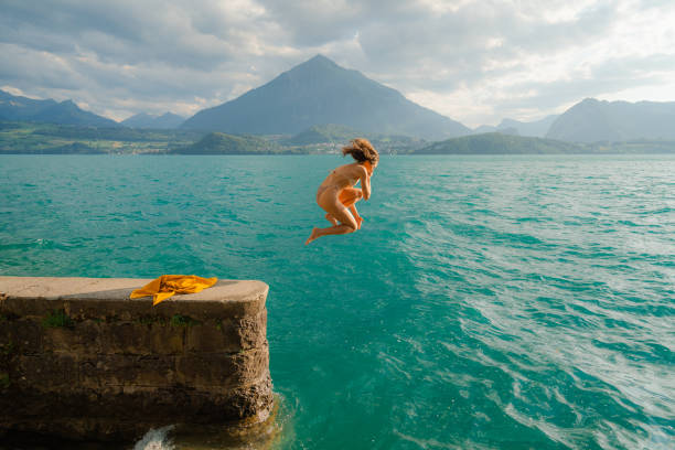 woman jumping into the lake in swiss alps - travel stock-fotos und bilder