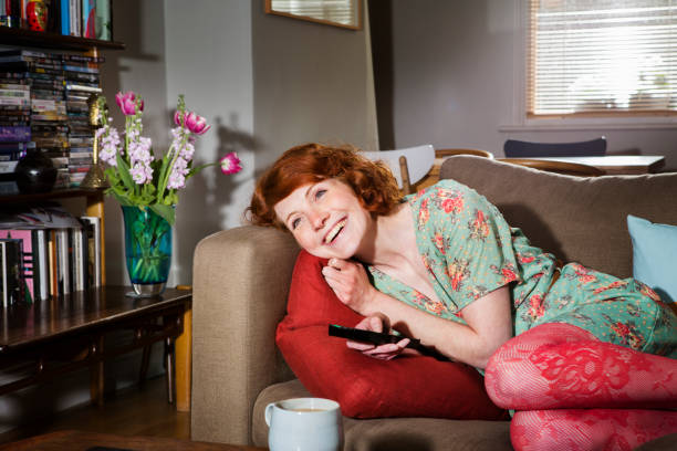 woman laughing while watching tv. - home decoration stock pictures, royalty-free photos & images