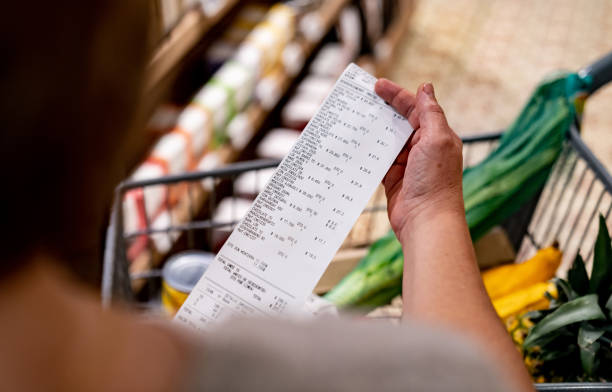 woman looking at a receipt after shopping at the supermarket - food stock pictures, royalty-free photos & images