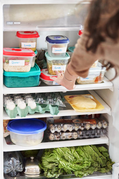 woman looking at healthy prepared meals in her fridge at home - food stock pictures, royalty-free photos & images