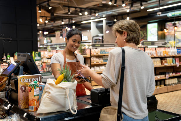 woman making a contactless payment at the supermarket - food stock pictures, royalty-free photos & images