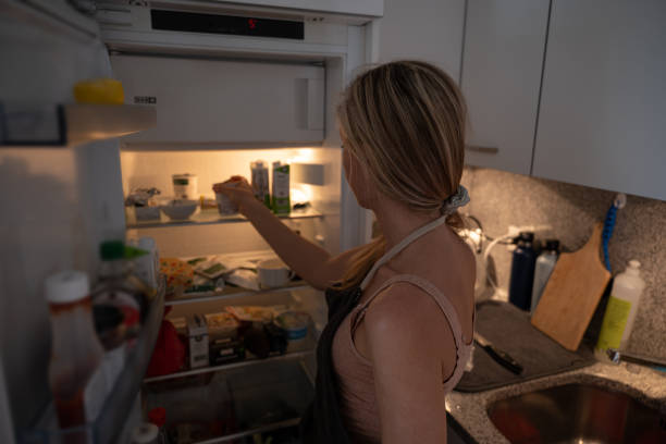 woman opens fridge and looks for ingredients - junk food stock pictures, royalty-free photos & images
