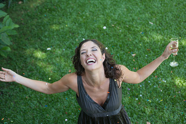 woman outdoors standing on grass with champagne and confetti smiling - garden decoration stock pictures, royalty-free photos & images