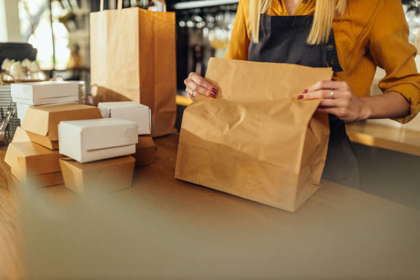 woman packing food in paper bags - junk food stock pictures, royalty-free photos & images
