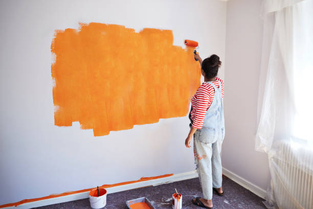 woman painting wall while renovating home - home decoration stockfoto's en -beelden