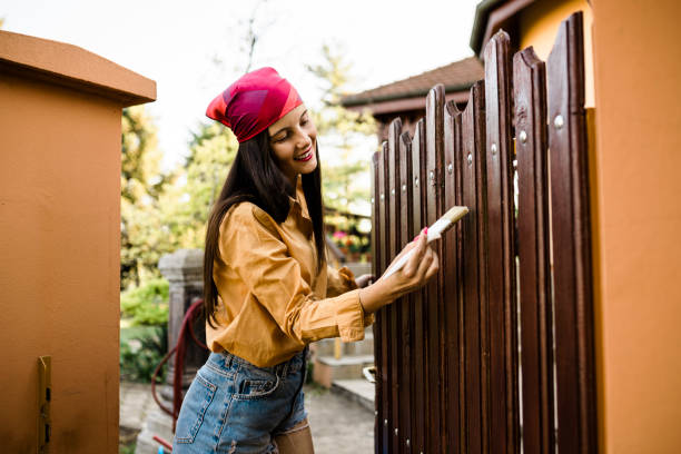 woman painting wooden fence at backyard. - home decoration stockfoto's en -beelden