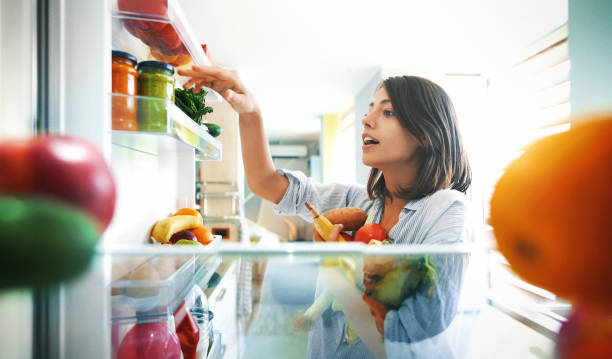 woman picking up some fruits and veggies from the fridge - food stock pictures, royalty-free photos & images