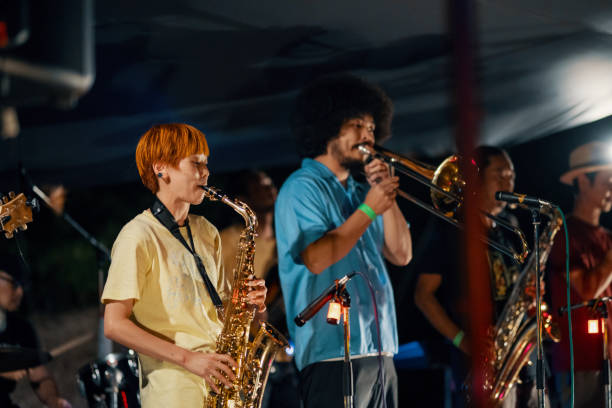 woman playing the saxophone at an outdoor music festival - concert stock pictures, royalty-free photos & images