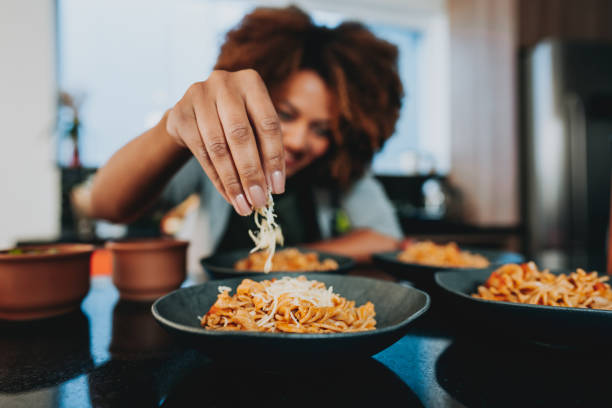 woman putting grated cheese on macaroni - food stock pictures, royalty-free photos & images