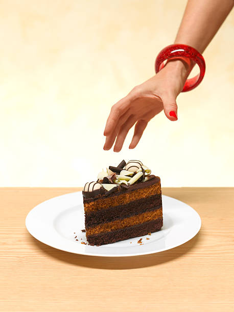woman reaching for a slice of cake - junk food stock pictures, royalty-free photos & images