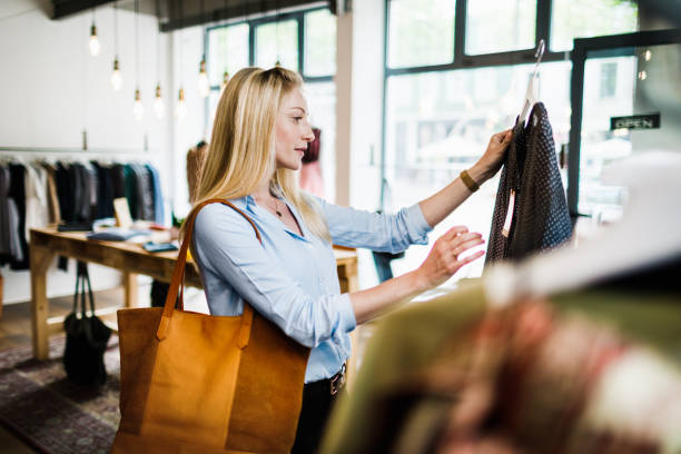 woman reading label on clothing while out shopping - fashion stock pictures, royalty-free photos & images