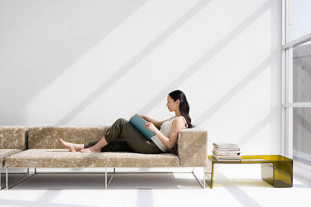 woman reading on a sofa - home decoration stock pictures, royalty-free photos & images