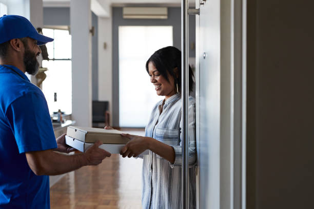 woman receiving pizza from delivery person - junk food stock pictures, royalty-free photos & images