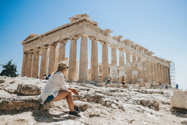 woman relaxing while looking at parthenon temple against clear sky - travel stock pictures, royalty-free photos & images