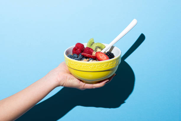woman's hand holding bowl with muesli - food stock pictures, royalty-free photos & images