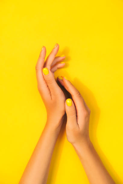 woman's hands with bright manicure are lying on yellow background. trendy colors of the year - nails art stock pictures, royalty-free photos & images