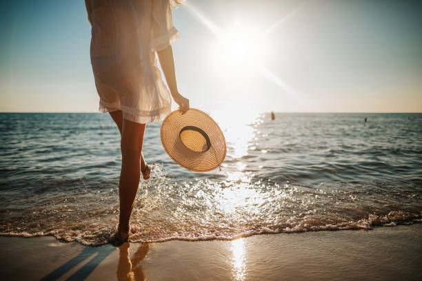 woman's legs splashing water on the beach - travel stock pictures, royalty-free photos & images