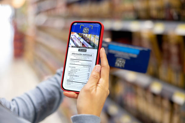 woman shopping at the supermarket and scanning a label with her cell phone - food stock pictures, royalty-free photos & images