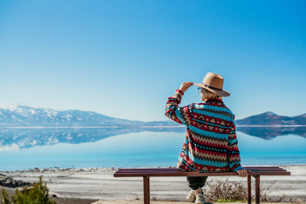 woman sitting near beautiful blue lake with white sand beach and enjoying its stunning view. salda lake, turkey - travel stockfoto's en -beelden