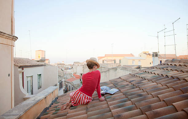 woman sitting on a tiled roof, reading cookbook - fashion stock pictures, royalty-free photos & images