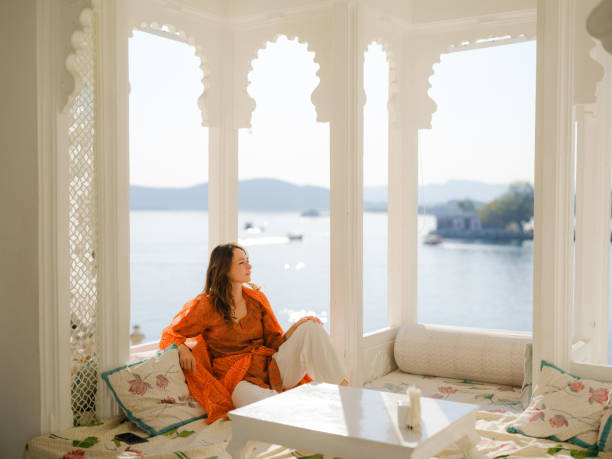 woman sitting on balcony during trip to udaipur - travel stockfoto's en -beelden