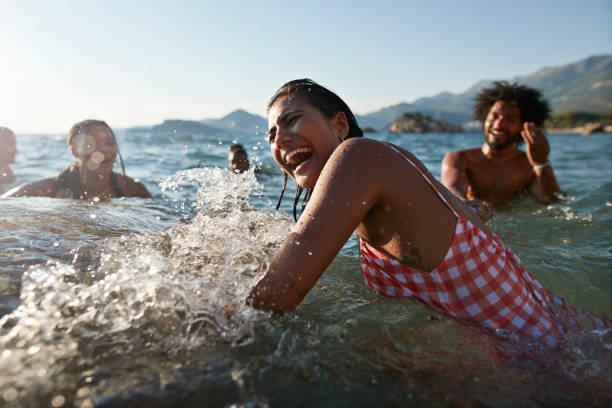 woman splashing and enjoying swim with friends - travel stock pictures, royalty-free photos & images
