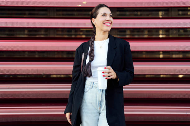 woman standing on the street and drinking coffee - junk food stock pictures, royalty-free photos & images