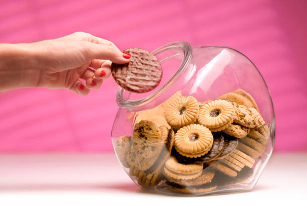 woman stealing biscuit, caught in the act. - junk food stock pictures, royalty-free photos & images